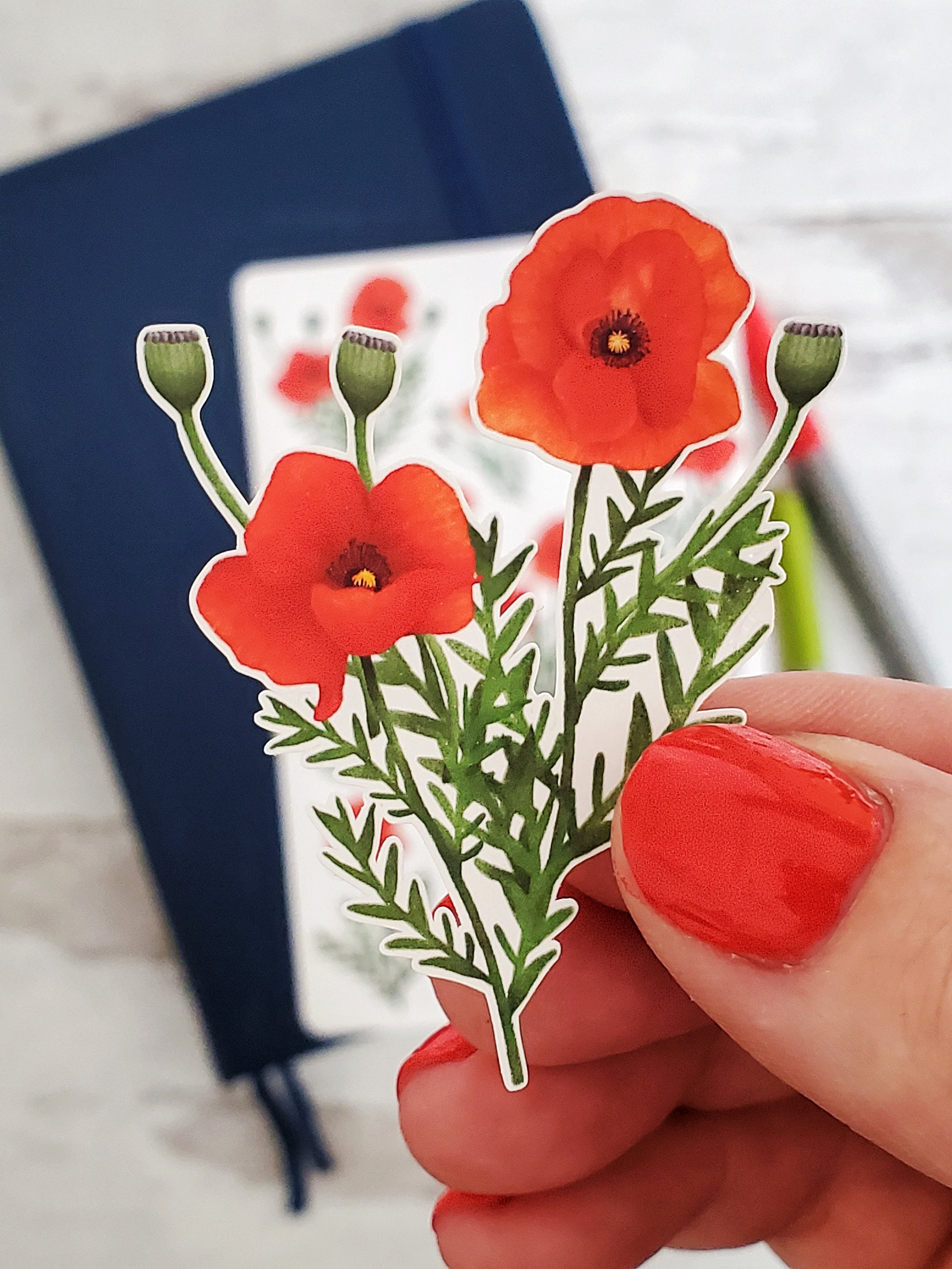 A close up of a sticker with two blooming red poppies and three buds