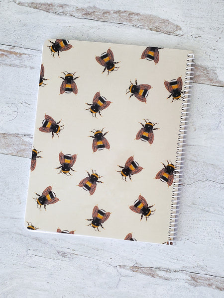 back cover of beige spiral notebook with illustrated bumble bee pattern 