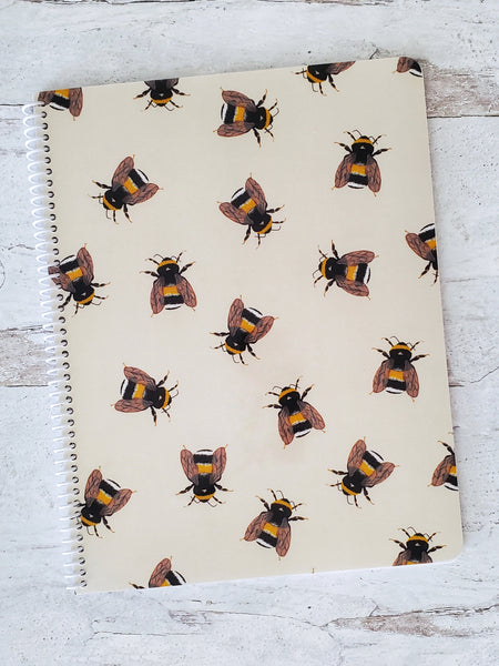 spiral notebook with illustrated bumble bee pattern on beige background