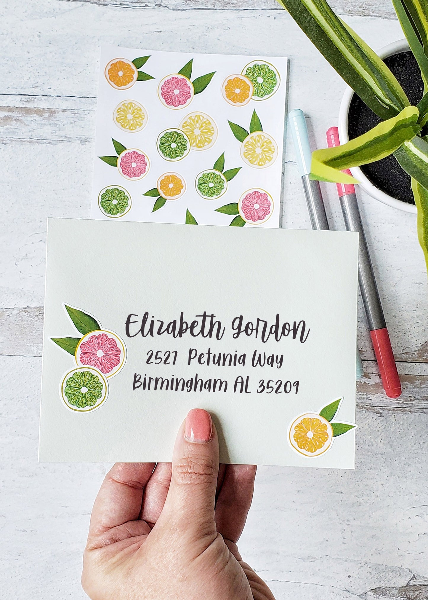 A mailing envelope decorated with an orange, lemon and pink grapefruit sticker.