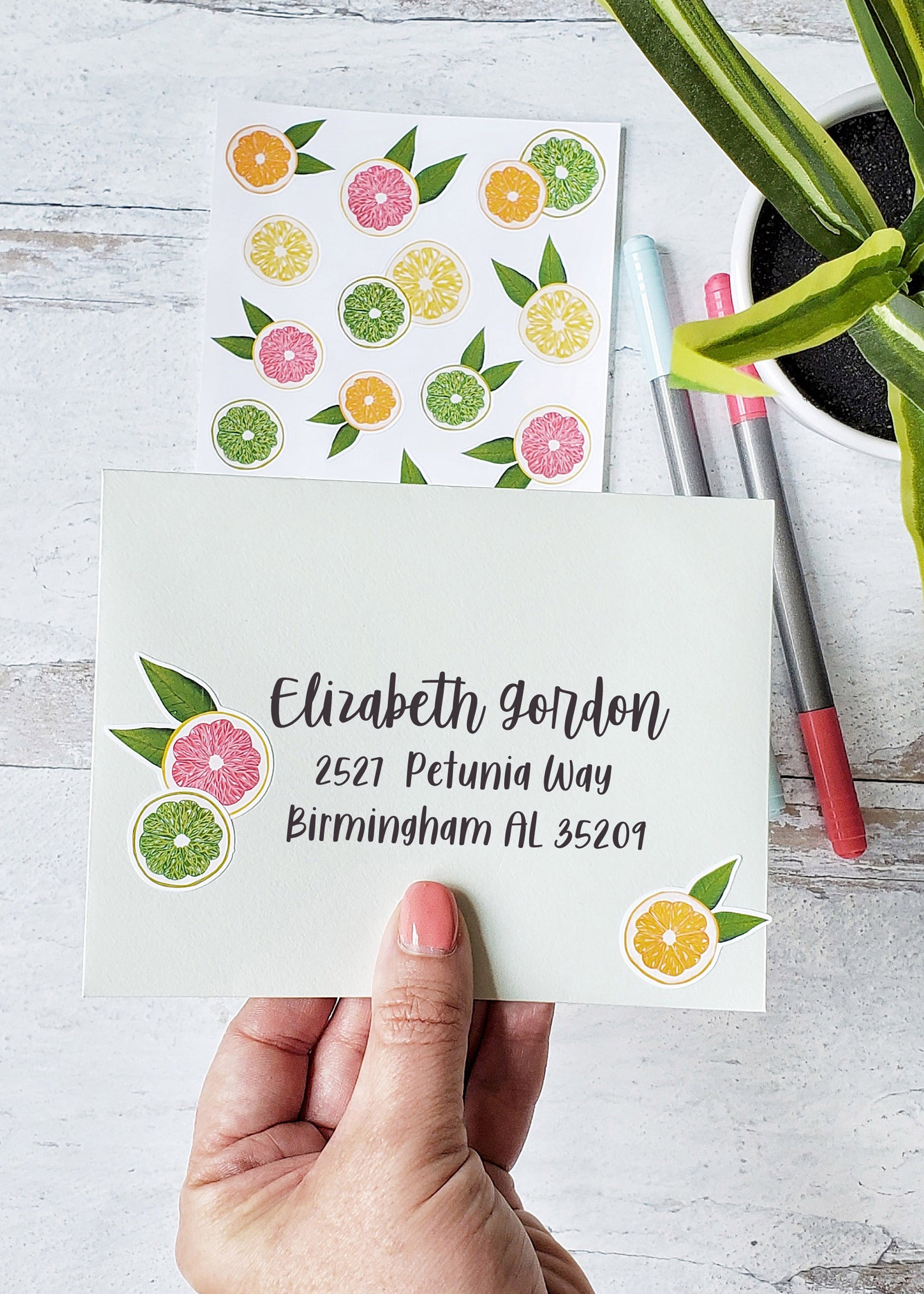 A mailing envelope decorated with an orange, lemon and pink grapefruit sticker.