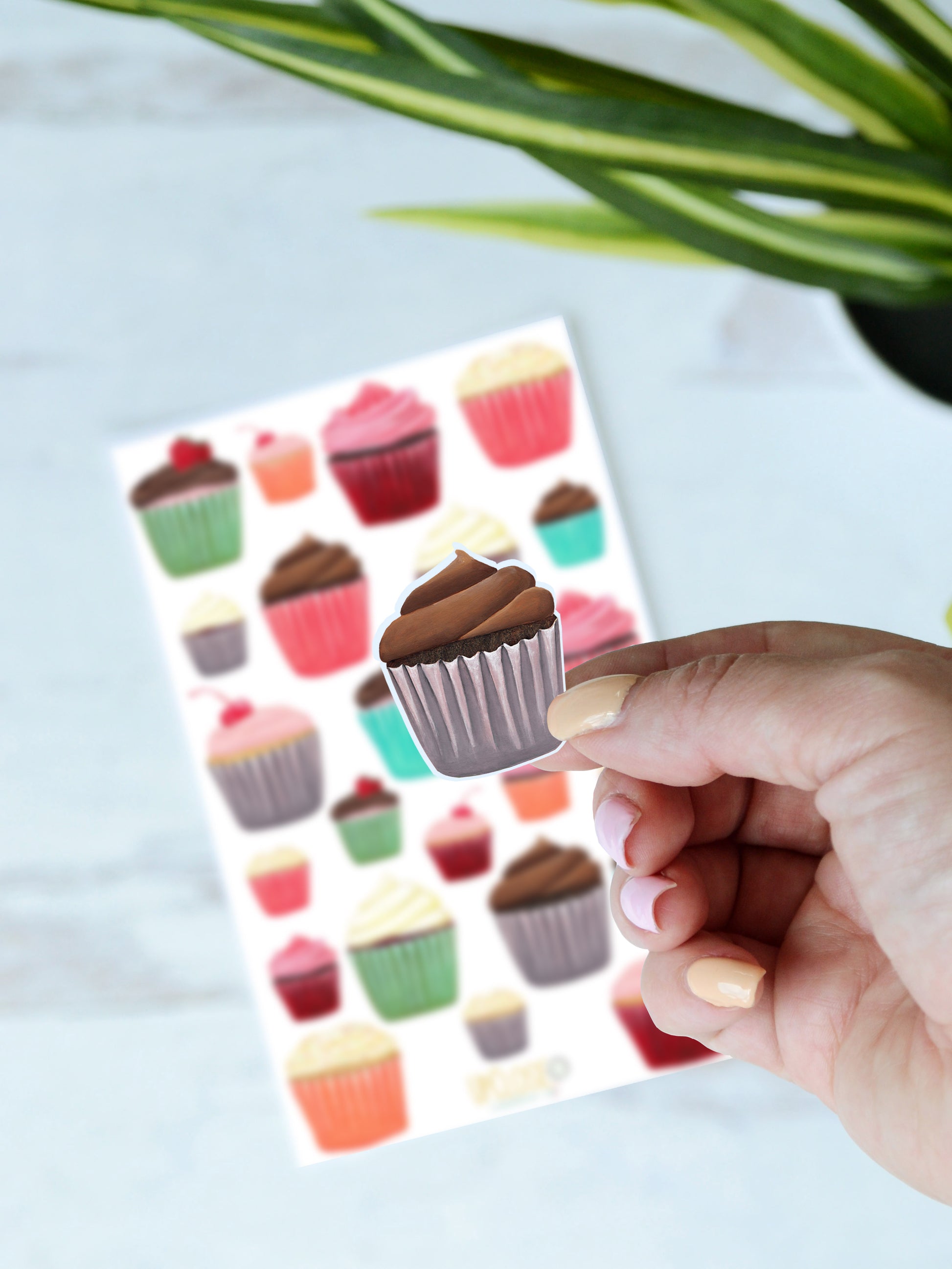 A close up of a chocolate cupcake sticker with a purple wrapper.