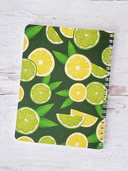 back cover of notebook with illustrated lemon and lime pattern on dark green background