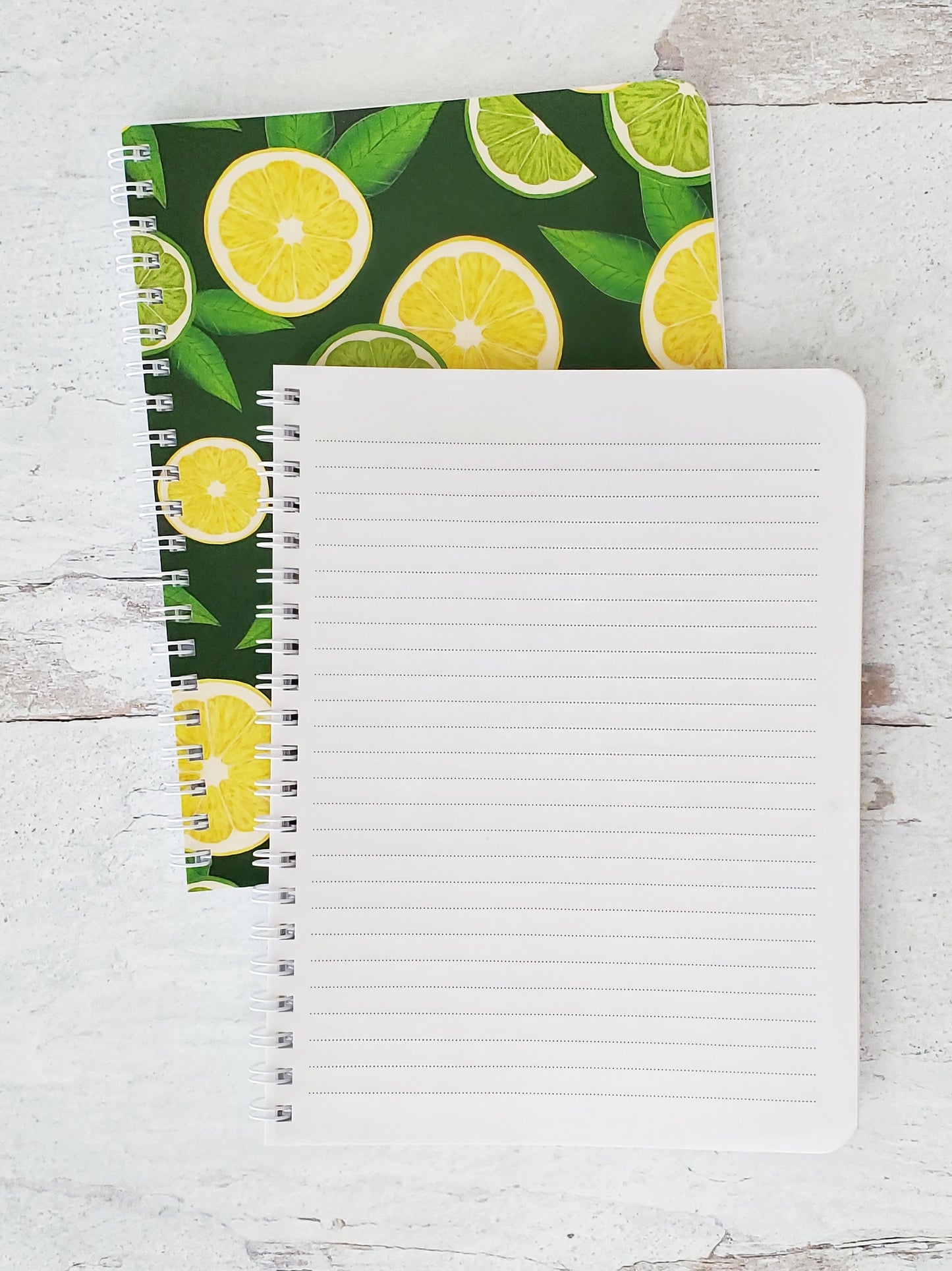notebook open to show lined pages on top of closed notebook showing lemon and lime pattern 