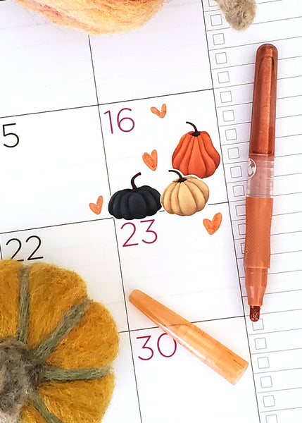 grouping of pumpkin stickers in the colors orange, cream and deep blue on a planner page