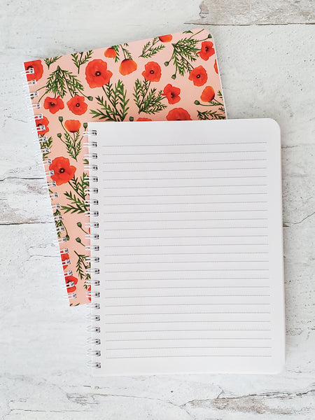 notebook opened to show lined pages sitting on top of closed notebook to show cover with red poppies pattern