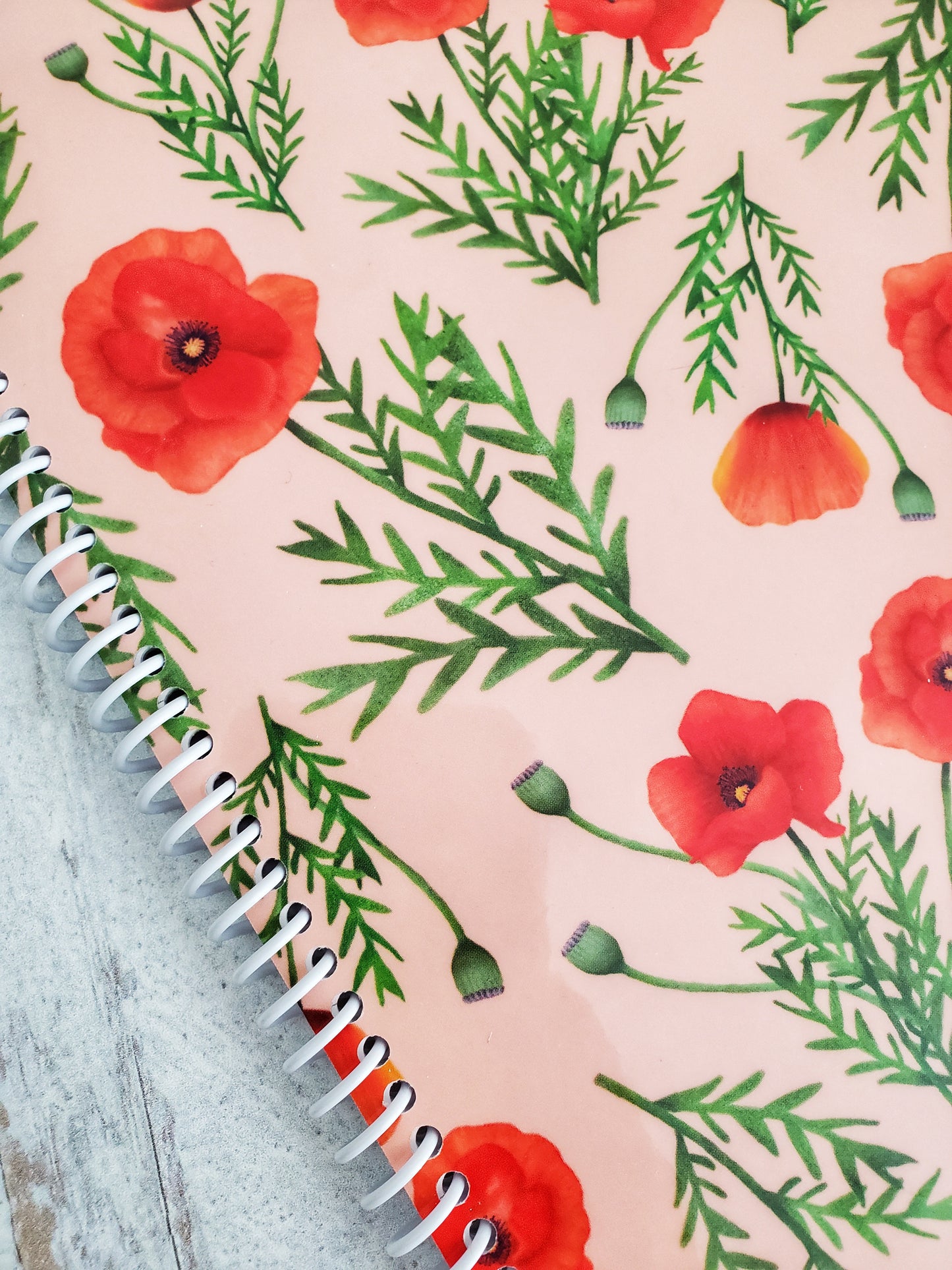 close up of red poppies illustrated artwork on the cover of a spiral notebook