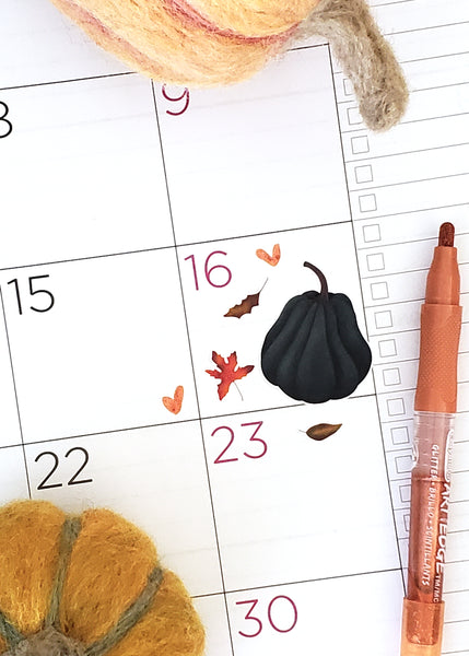 deep blue tall pumpkin and fall leaves on a planner page 