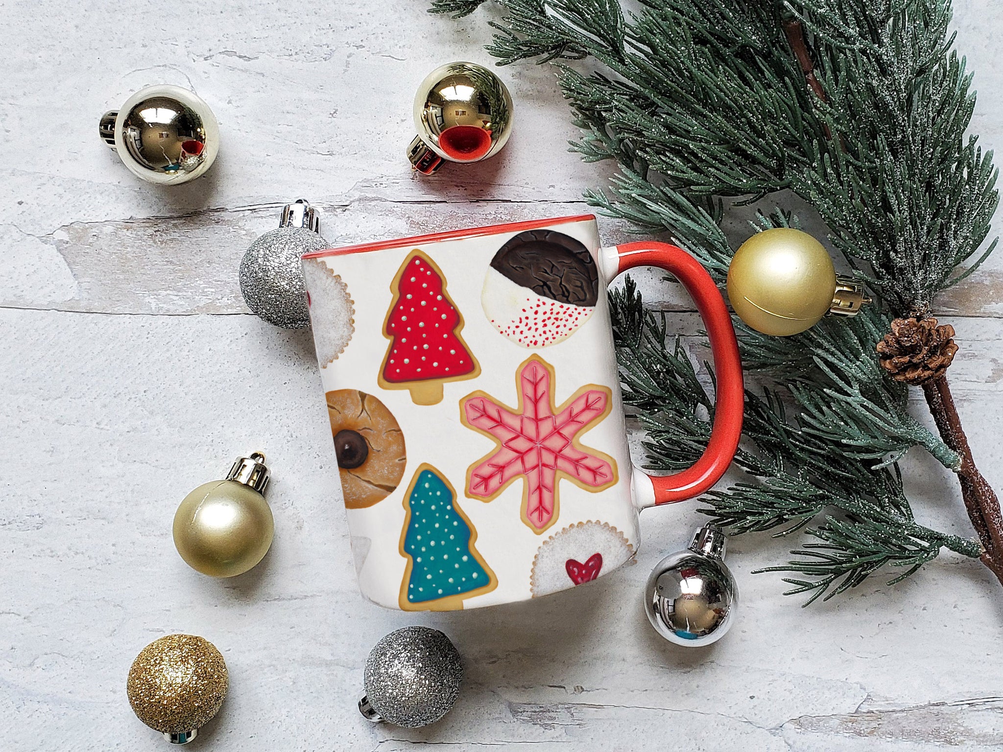 ceramic mug with Illustrated Christmas cookies pattern and a red handle styled with gold and silver ornaments and a tree bough