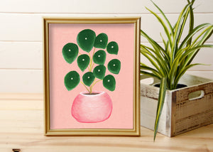 print of pilea plant on pink background in gold frame