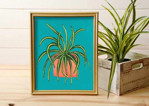 print of hand painted spider plant on turquoise background in gold frame