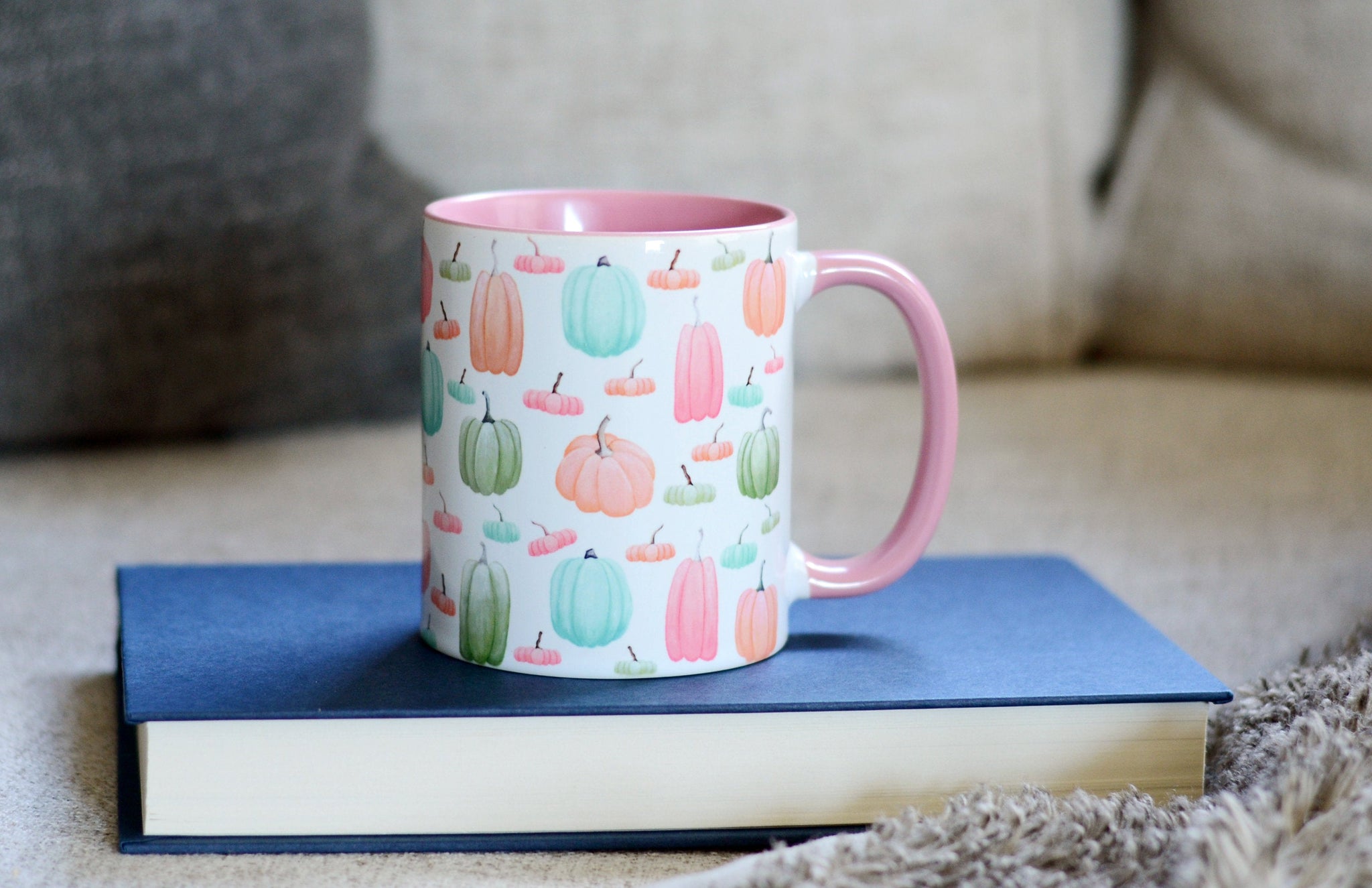 ceramic mug with pink handle and interior wrap around  pattern is hand painted pink green orange and blue pumpkin illustrations on white background