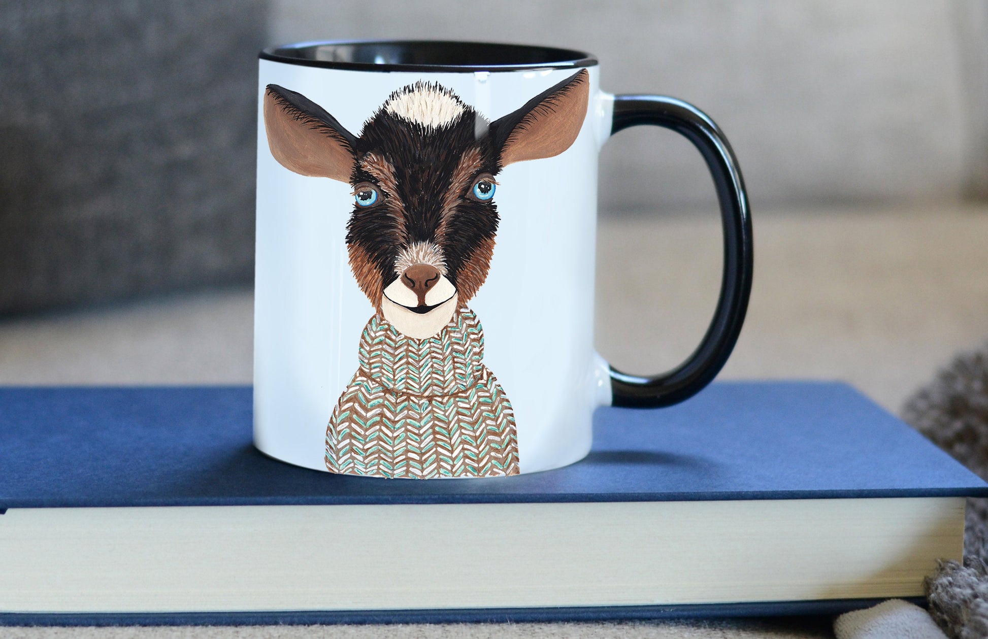 sweater goat mug sitting on a book with comfy couch in the background