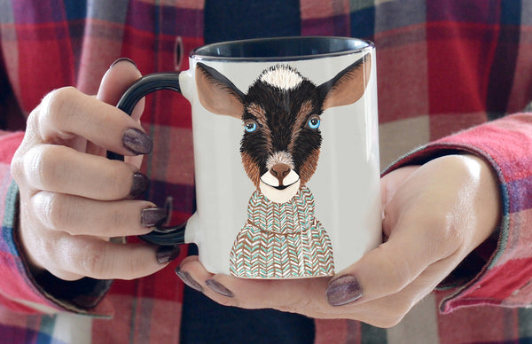 ceramic mug with black handle and interior features hand painted black and brown goat bust wearing a knit blue and brown sweaterng