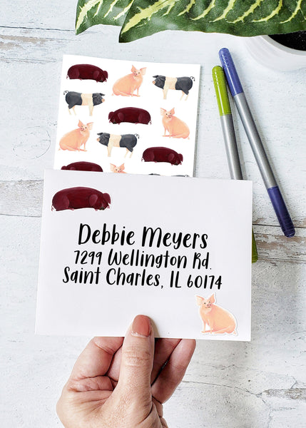 red laying down pig sticker and pink sitting pig sticker decorating an envelope